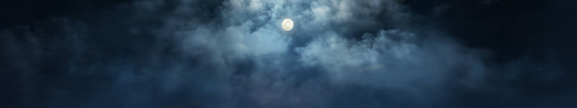The moon shining thru the clouds on a dark night.